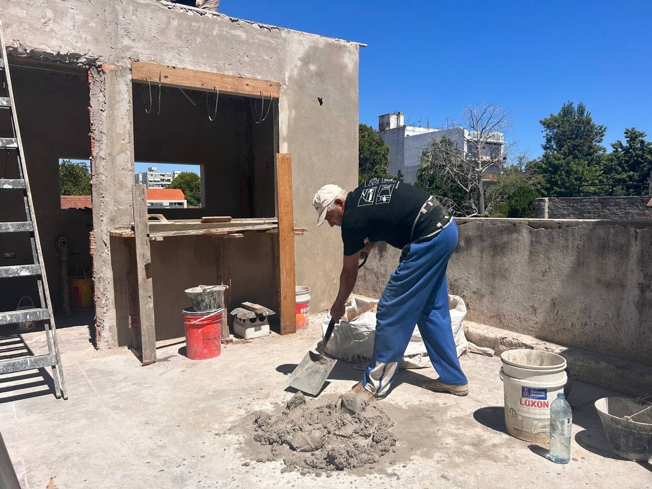 Operario mezclando material en una obra en construcción, a cielo abierto