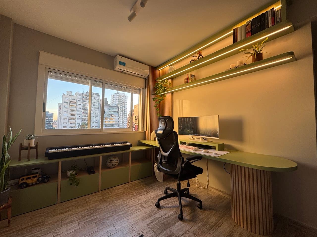 Escritorio en tonos verde oliva con estantería de madera e iluminación integrada